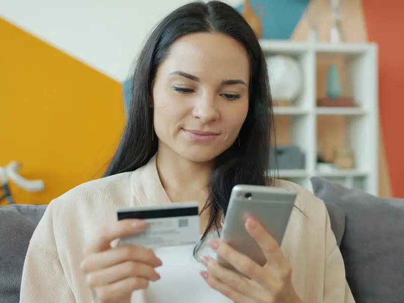 Mujer en su sala revisando una compra en línea desde el celular